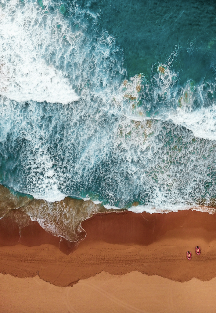 a beach with waves and a couple of pink rafts